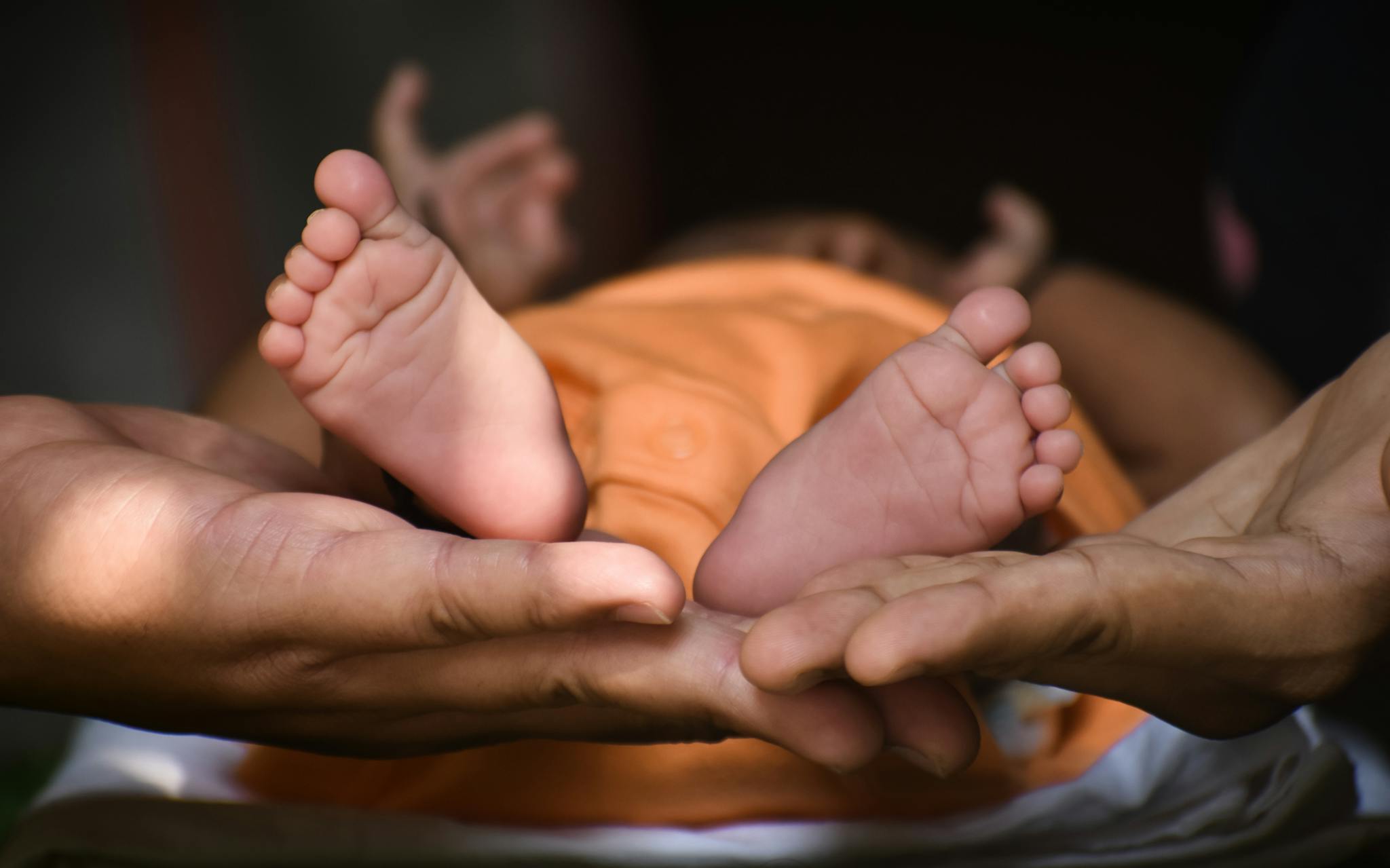 Tender moment showing newborn baby feet cradled by parent's hands, symbolizing love and care.